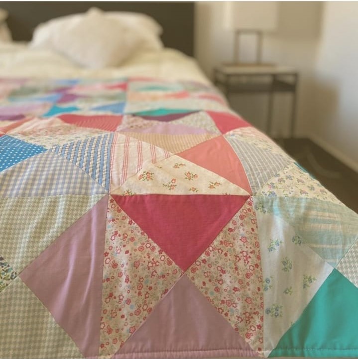 Triangle-pieced patchwork quilt in pastel florals on a bed